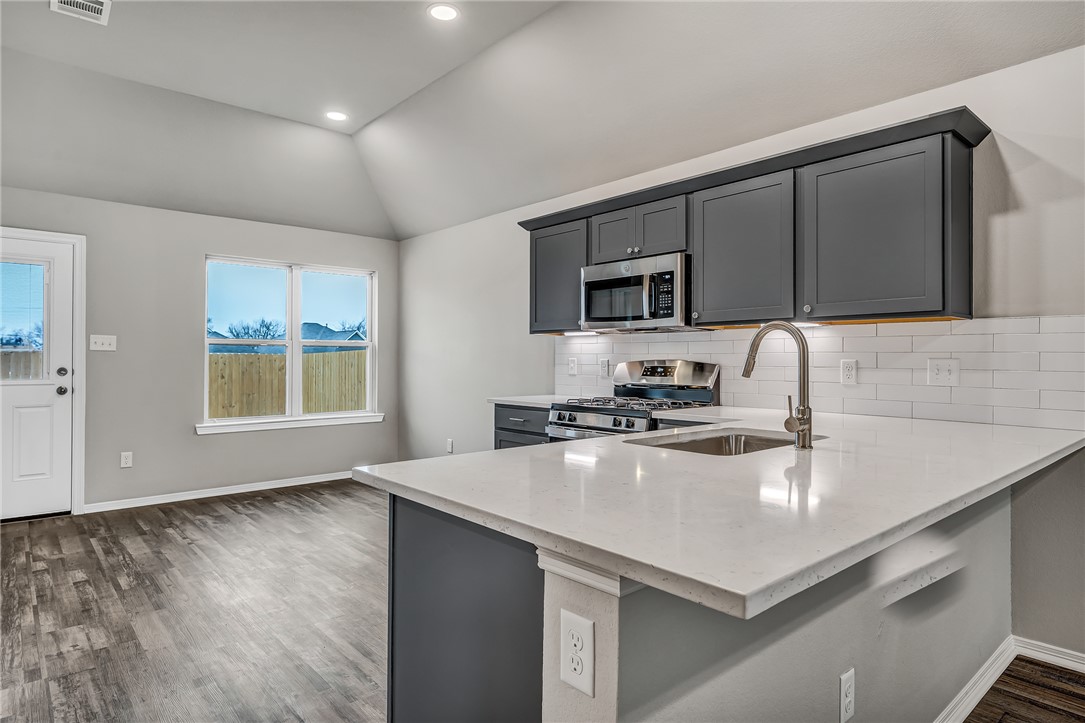 1231 High Street Navasota, TX 77868 - Photo 6 of 18 a kitchen with a sink a stove a microwave and wooden cabinets