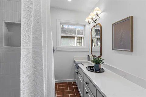 a bathroom with a sink a mirror and a potted plant