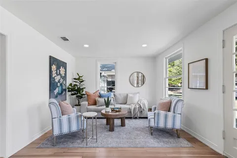 a living room with furniture a clock on wall and a window