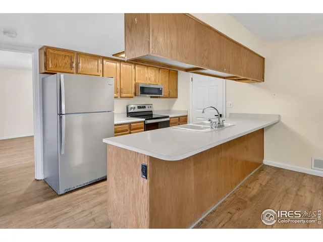 a kitchen with stainless steel appliances granite countertop a sink a refrigerator and a wooden floor