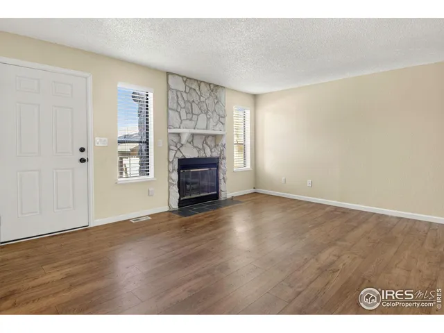 a view of empty room with wooden floor and fireplace