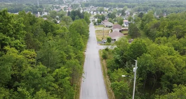 an aerial view of residential house with outdoor space and trees all around