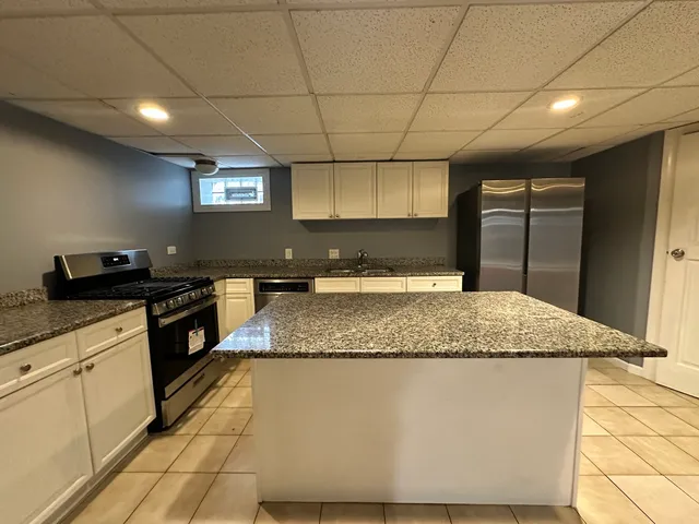 a kitchen with kitchen island granite countertop a sink a counter top space and cabinets