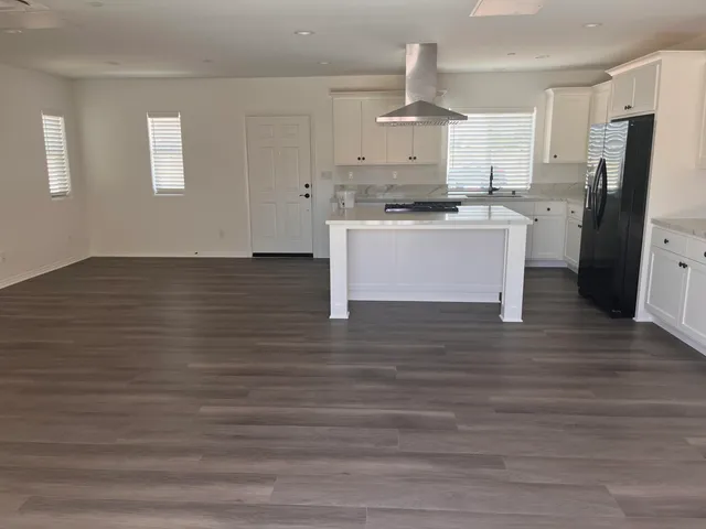 a view of kitchen with stainless steel appliances granite countertop a stove a refrigerator white cabinets and wooden floor