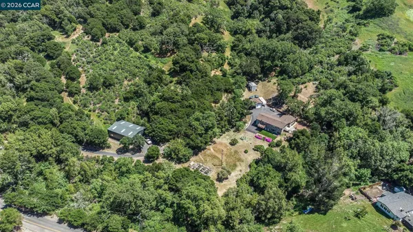 an aerial view of residential house with outdoor space and trees all around