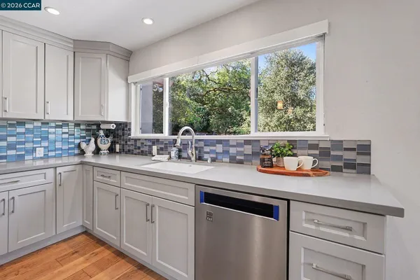 a kitchen with stainless steel appliances granite countertop white cabinets and a window