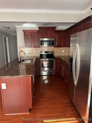 a kitchen with stainless steel appliances granite countertop a refrigerator a stove a sink and a microwave