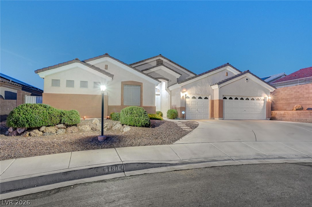 1604 Cattle Ranch Place Henderson, NV 89002 - Photo 3 of 99 A desert-friendly landscape surrounds this welcoming residence, featuring a curved driveway and dual garages.