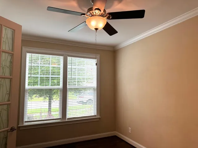 a view of an empty room with window and chandelier fan