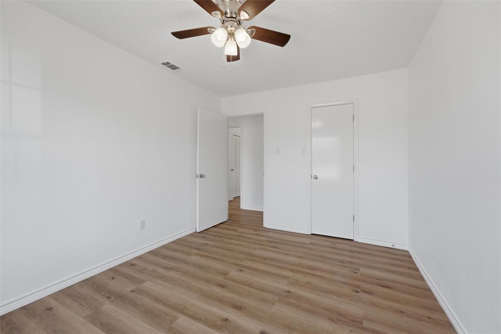 124 Prairie Creek Road Red Oak, TX 75154 - Photo 11 of 17 Spacious bedroom featuring wood-finish flooring, ceiling fan with integrated lighting, and dual closet access