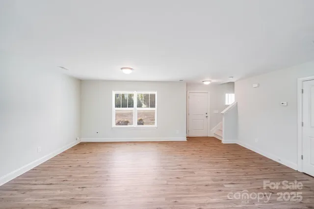 a view of empty room with wooden floor and window