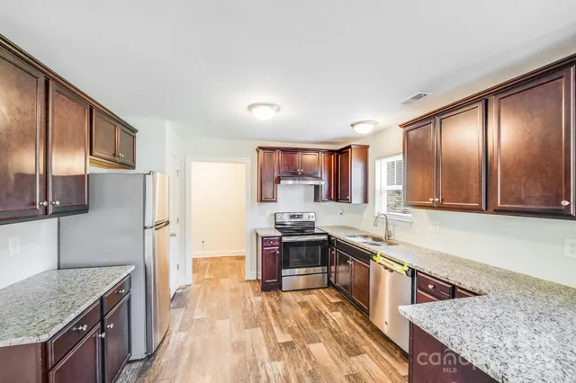 a kitchen with stainless steel appliances granite countertop a stove a sink and a refrigerator