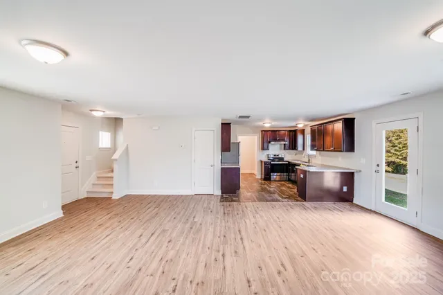 a view of empty room with kitchen and window