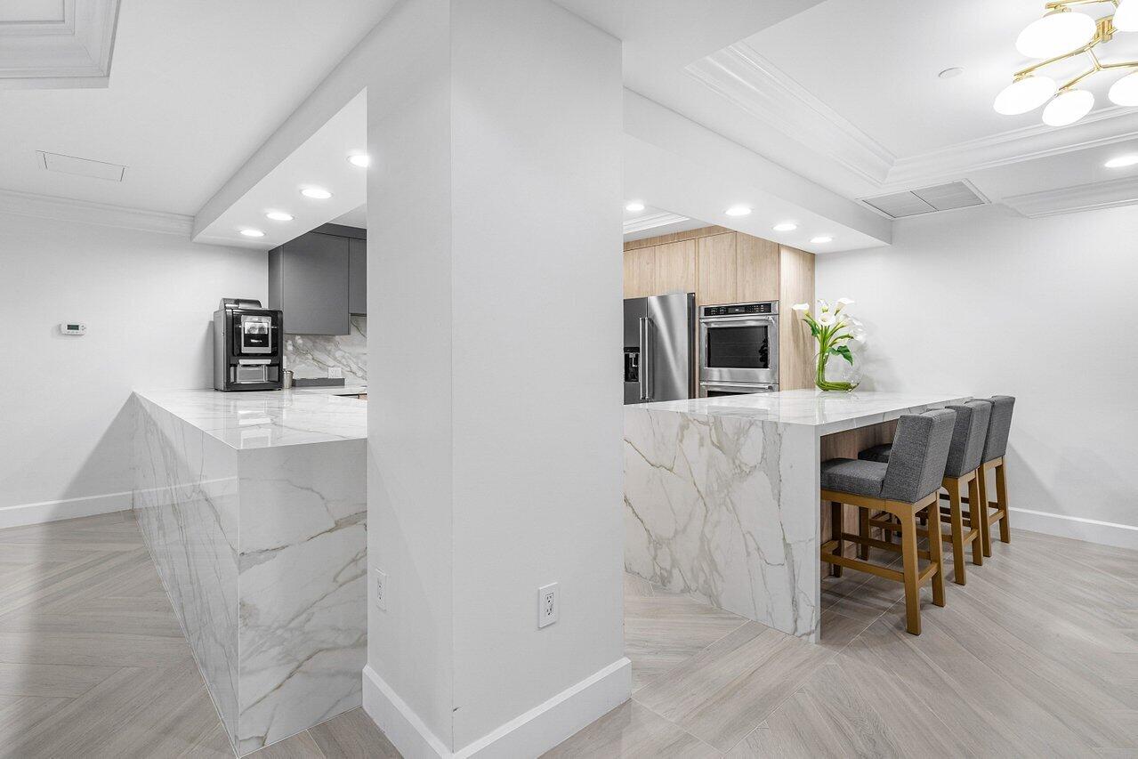 500 Southeast Mizner Boulevard, Unit A411 Boca Raton, FL 33432 - Photo 58 of 67 a kitchen with stainless steel appliances kitchen island granite countertop a table chairs and a refrigerator