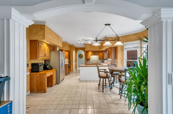 a dining room filled with lots of tables a chandelier and kitchen view