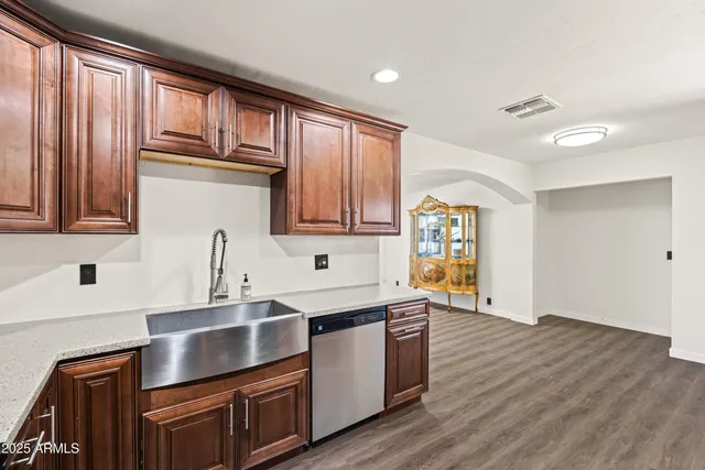 a kitchen with stainless steel appliances granite countertop a sink dishwasher stove and wooden cabinets with wooden floor