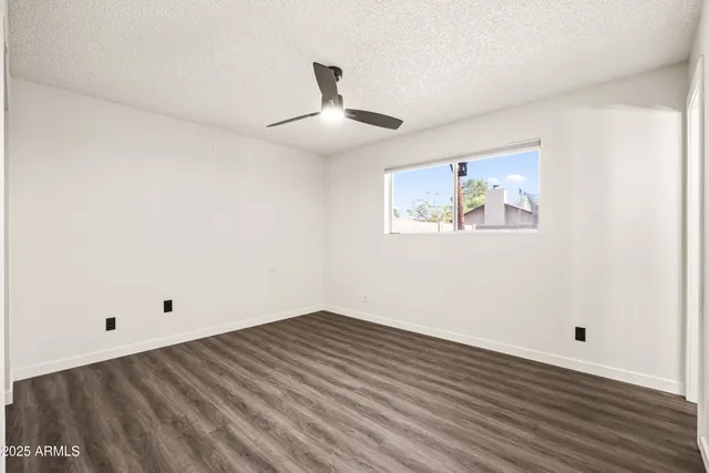 an empty room with wooden floor and ceiling fan