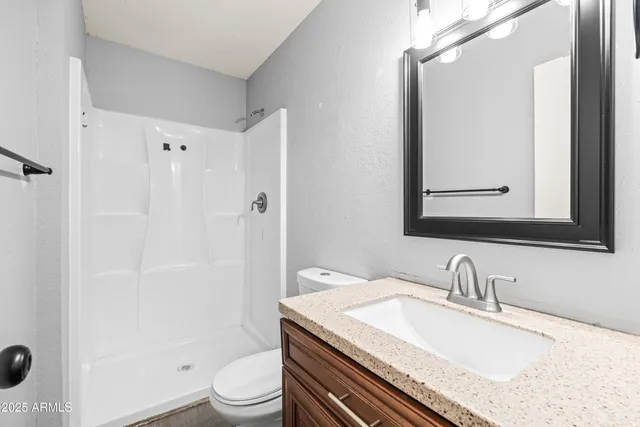 a bathroom with a granite countertop sink toilet a mirror and shower