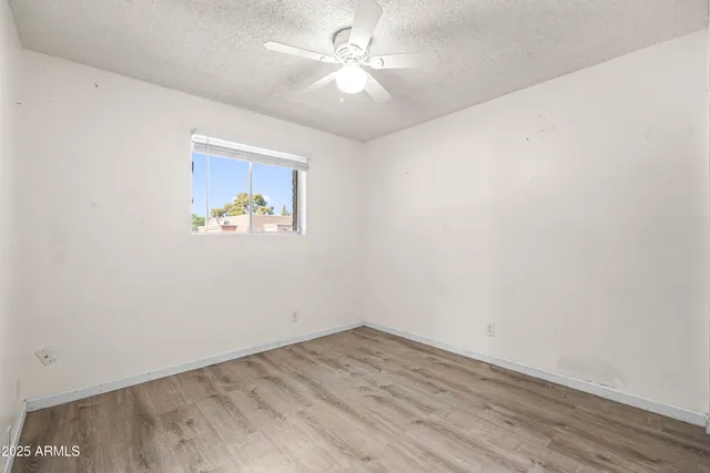 an empty room with a window and a ceiling fan