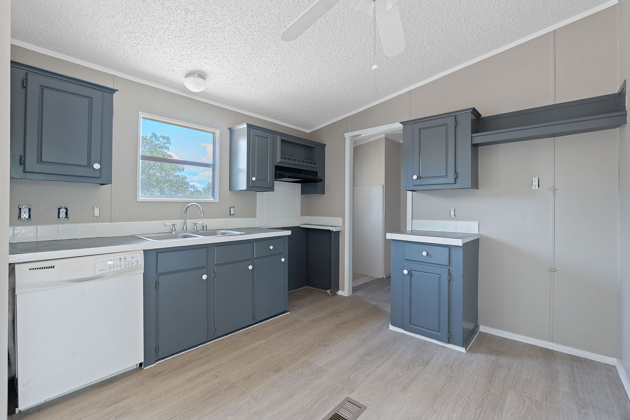 1385 Pettytown Road Dale, TX 78616 - Photo 4 of 17 Kitchen featuring white dishwasher, light countertops, light wood finished floors, a textured ceiling, and vaulted ceiling