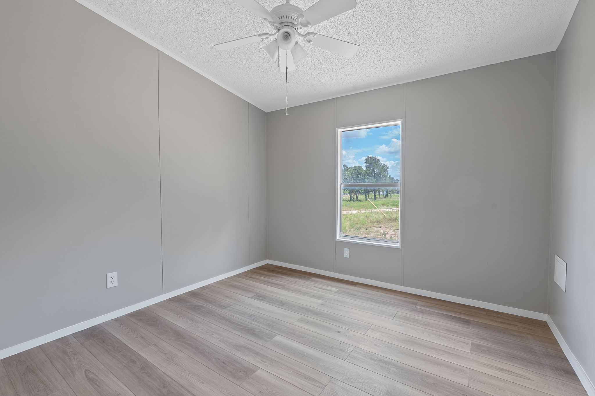 1385 Pettytown Road Dale, TX 78616 - Photo 9 of 17 Unfurnished room featuring light wood finished floors, a textured ceiling, and a ceiling fan