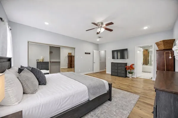 a spacious bedroom with a bed and a flat screen television
