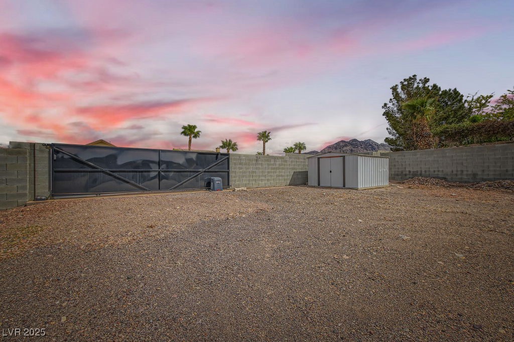 647 Foxhall Road Henderson, NV 89002 - Photo 57 of 82 Yard at dusk featuring an outbuilding, a fenced backyard, and a storage shed