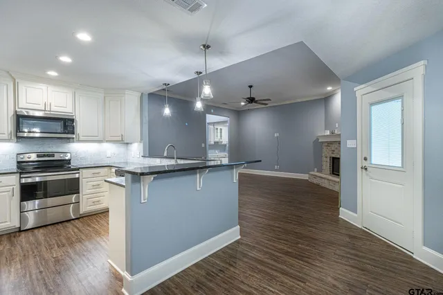 a large kitchen with stainless steel appliances granite countertop a stove and a refrigerator