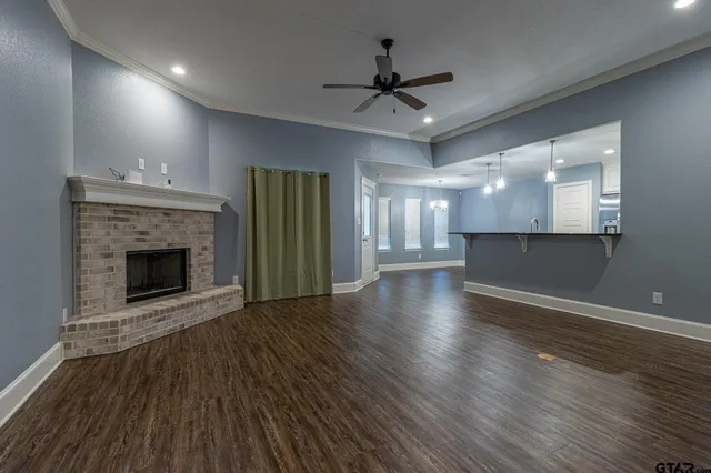 a view of a livingroom with a fireplace a ceiling fan and wooden floor