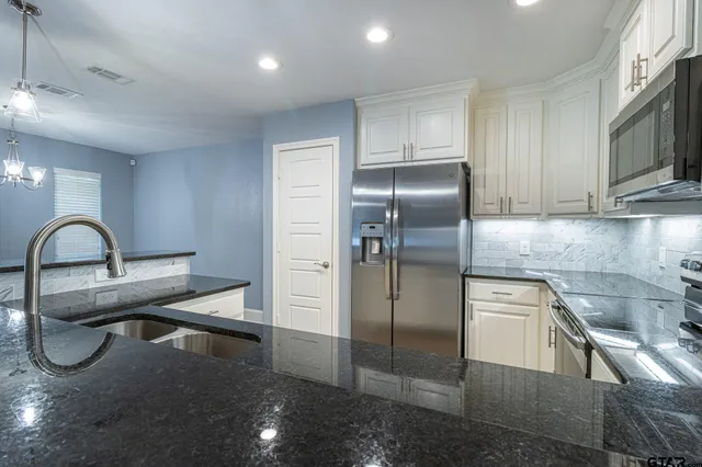 a kitchen with stainless steel appliances granite countertop a sink a stove and a refrigerator