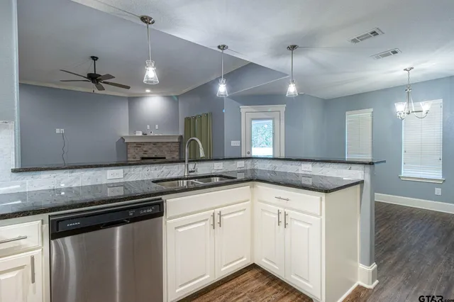 a kitchen with a sink dishwasher and white cabinets with wooden floor
