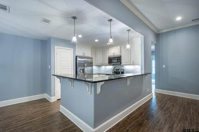 a kitchen with stainless steel appliances granite countertop a sink cabinets and wooden floor