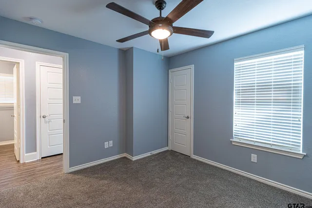 an empty room with windows and fan