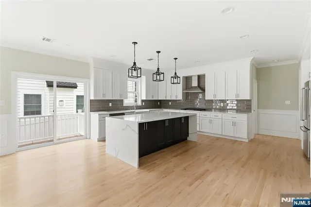 a large kitchen with kitchen island a sink a stove and white cabinets