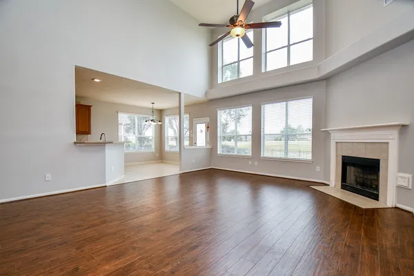 a view of an empty room with wooden floor and a fireplace