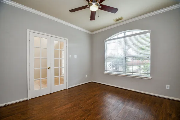 a view of an empty room with wooden floor and a window
