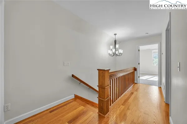 a view of a hallway with wooden floor and staircase