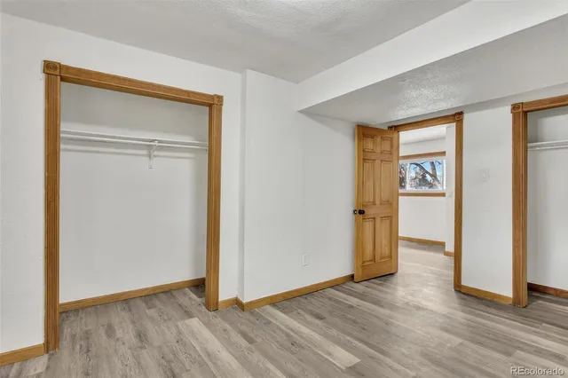 an empty room with wooden floor closet and windows