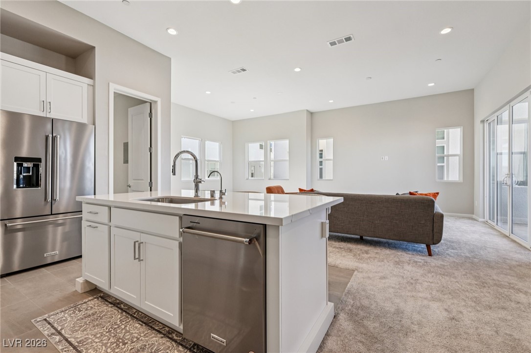 3338 Esker Rdg Avenue Henderson, NV 89044 - Photo 80 of 84 Kitchen featuring appliances with stainless steel finishes, white cabinets, open floor plan, a kitchen island with sink, and light stone countertops