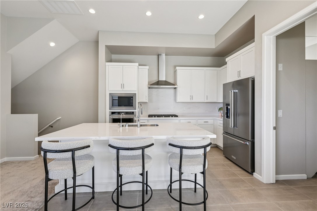 3338 Esker Rdg Avenue Henderson, NV 89044 - Photo 13 of 84 Kitchen with appliances with stainless steel finishes, white cabinetry, light stone countertops, a breakfast bar, and a center island with sink