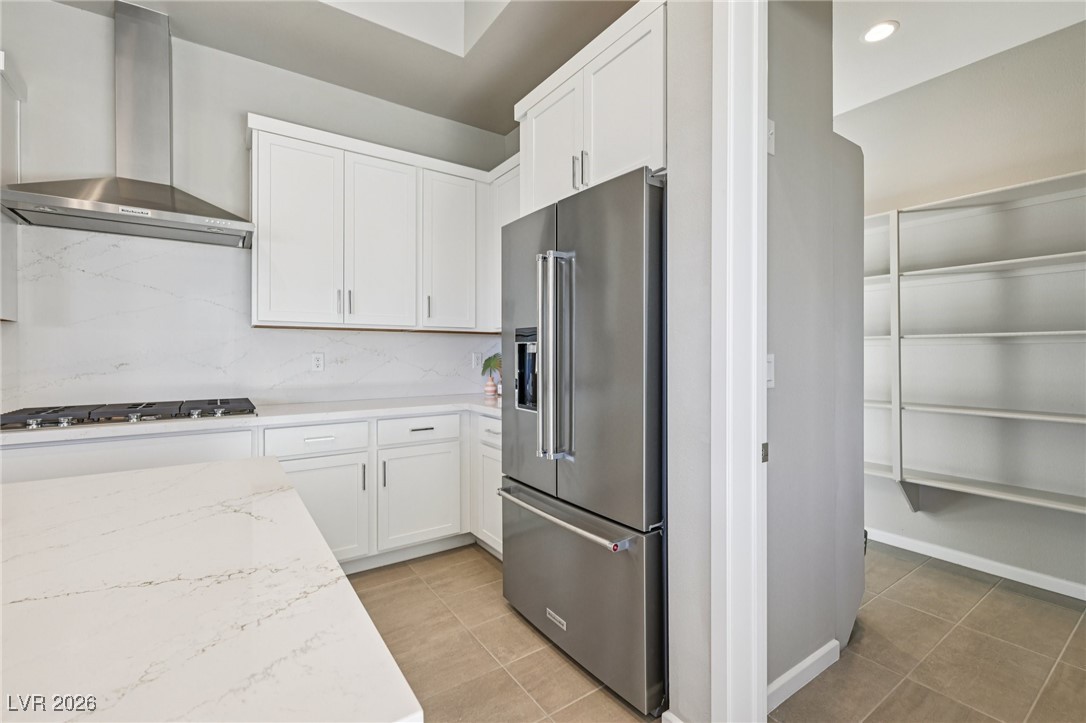 3338 Esker Rdg Avenue Henderson, NV 89044 - Photo 16 of 84 Kitchen with wall chimney range hood, stainless steel appliances, white cabinetry, light stone counters, and recessed lighting