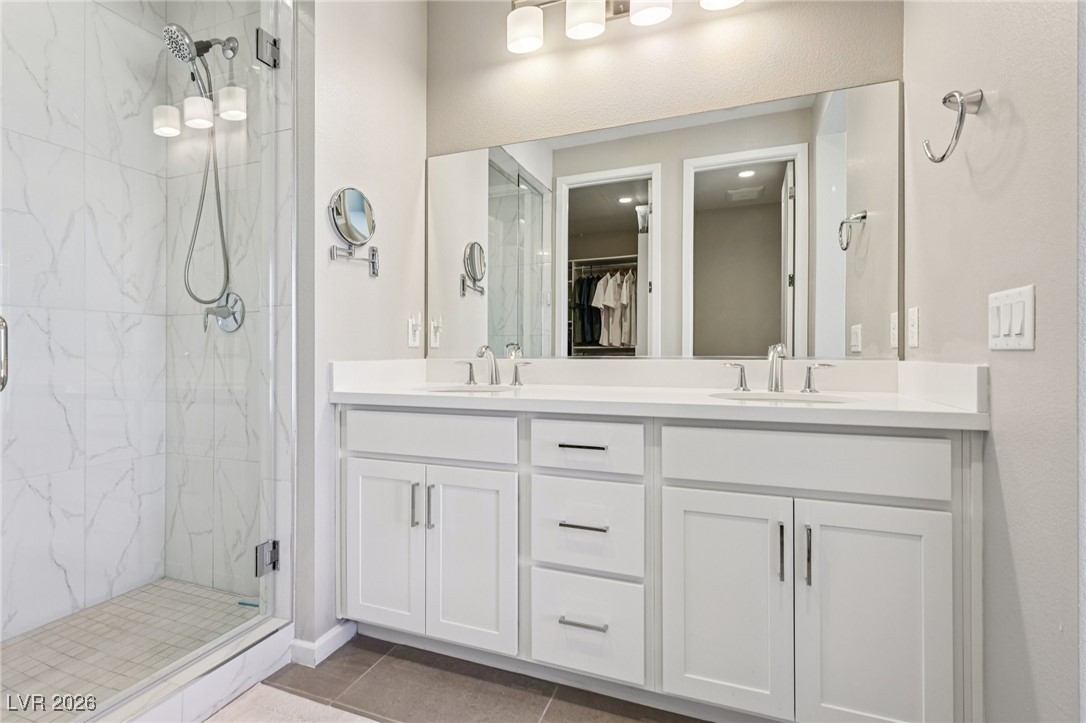 3338 Esker Rdg Avenue Henderson, NV 89044 - Photo 35 of 84 Bathroom with double vanity, a marble finish shower, a walk in closet, and light tile patterned flooring