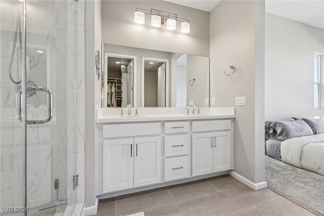 3338 Esker Rdg Avenue Henderson, NV 89044 - Photo 36 of 84 Ensuite bathroom with double vanity, a marble finish shower, a spacious closet, and light tile patterned flooring