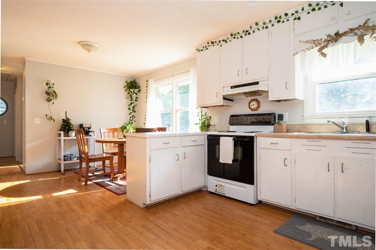 4005 Lizard Lick Road Wendell, NC 27591 - Photo 17 of 25 a kitchen with a stove a sink and white cabinets with wooden floor