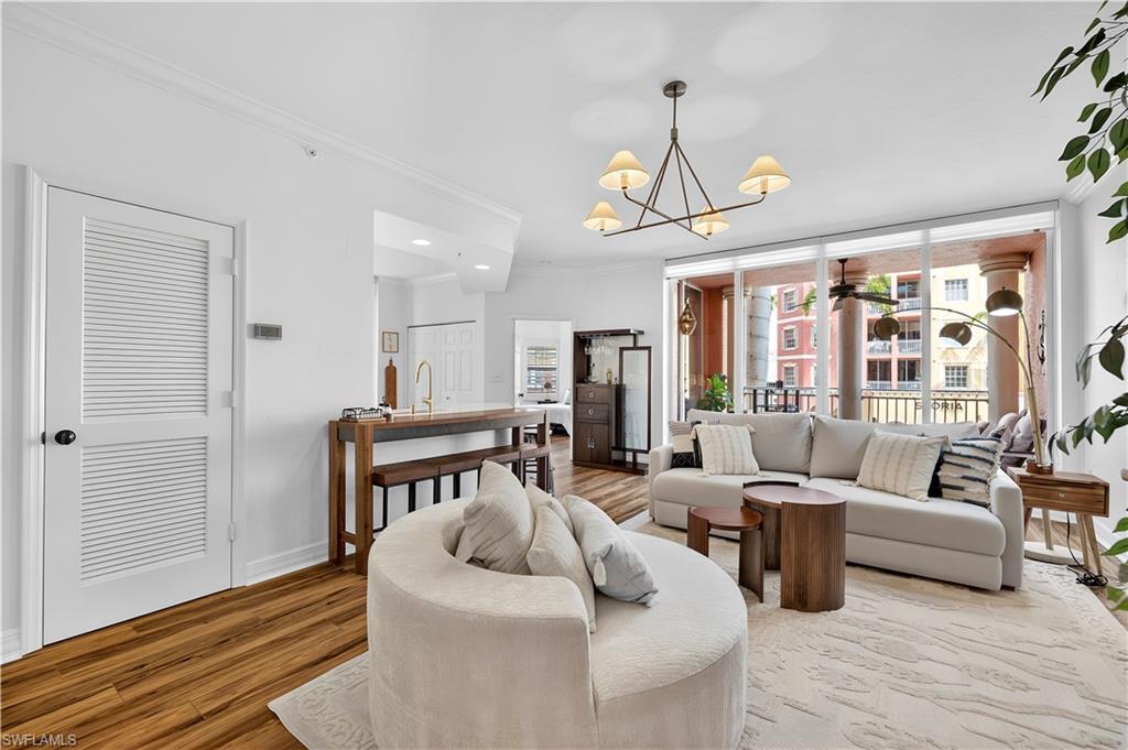 450 Bayfront Place, Unit 4202 Naples, FL 34102 - Photo 5 of 39 Living area featuring ornamental molding, suspended lighting, wood finished floors, and a ceiling fan