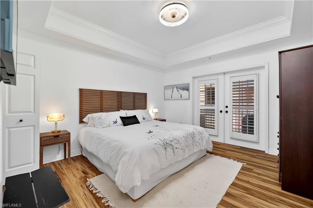 450 Bayfront Place, Unit 4202 Naples, FL 34102 - Photo 6 of 39 Bedroom featuring light wood-type flooring, crown molding, french doors, a tray ceiling, and access to exterior