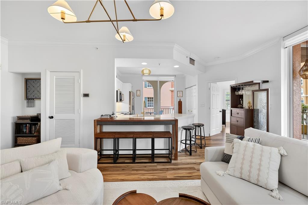 450 Bayfront Place, Unit 4202 Naples, FL 34102 - Photo 10 of 39 Living area featuring ornamental molding, light wood-style floors, and hanging lights