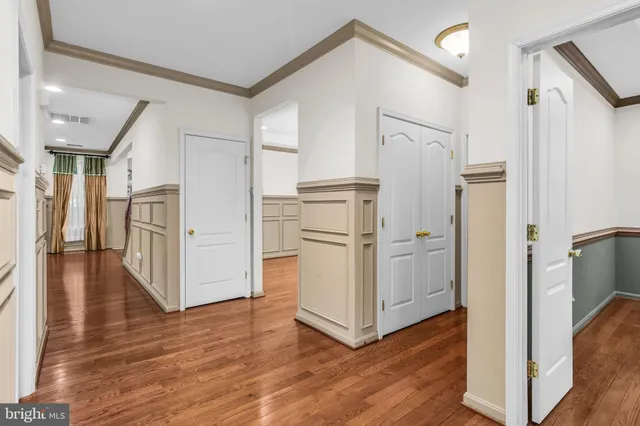 a view of a hallway with wooden floor and cabinets