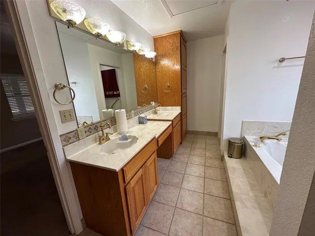 a bathroom with a double vanity sink mirror and bathtub