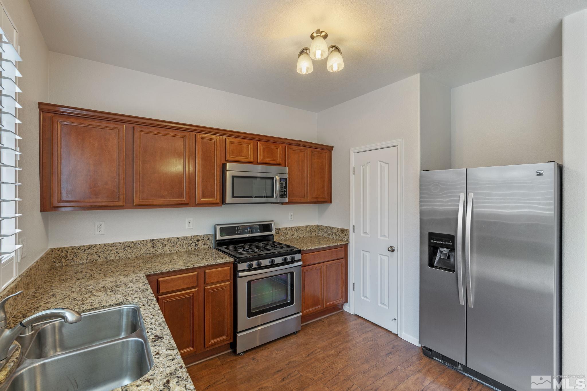 310 Pesaro Way Reno, NV 89521 - Photo 11 of 25 a kitchen with stainless steel appliances granite countertop a refrigerator a stove and a sink with wooden floor